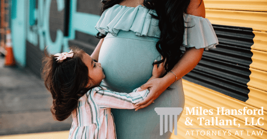 little girl kissing her mom's pregnant stomach