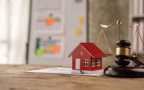 Toy house on top of documents with gavel